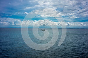 Traditional fisherboat sailing on water with cloudy sky