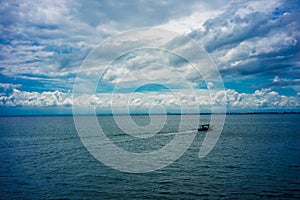 Traditional fisherboat sailing on water with cloudy sky