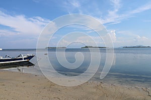 Traditional fishing boat moored at sandy beach using an anchor rope. Laminate boat with wooden roof tied up by shore at low tide.