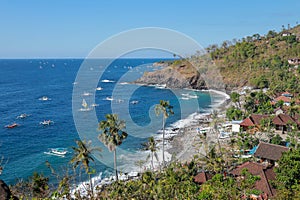 Traditional fishing boats go to the safety of the bay in Bali. A rock island off the coast with tropical vegetation.