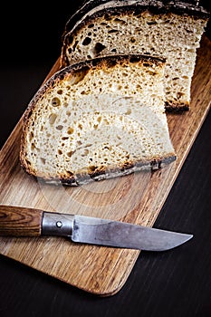 Traditional French country bread slices and pocket knife on a cutting board