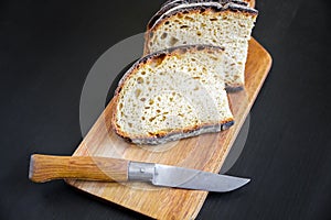 Traditional French country bread slices and pocket knife on a cutting board