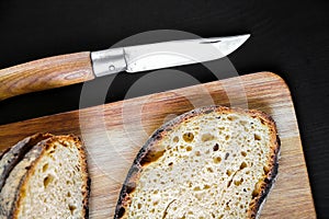 Traditional French country bread slices and pocket knife on a cutting board