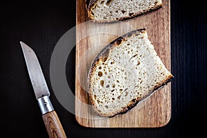 Traditional French country bread slices and pocket knife on a cutting board