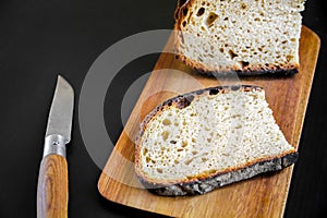 Traditional French country bread slices and pocket knife on a cutting board