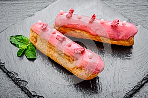 Traditional French dessert. Eclair with chocolate icing and raspberries.