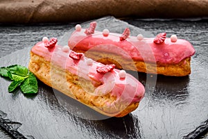 Traditional French dessert. Eclair with chocolate icing and raspberries.
