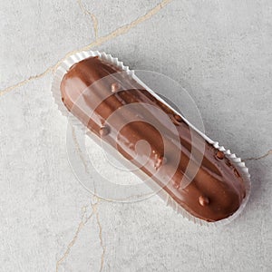 Traditional french dessert. eclair with custard and chocolate icing on a stone background. Pastry products for sweet