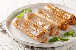 Traditional French dessert Eclairs with custard and topped with caramels icing close-up in a plate. Horizontal