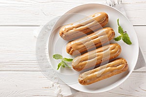 Traditional French dessert Eclairs with custard and topped with caramels icing close-up in a plate. Horizontal top view
