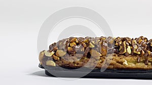 Traditional french dessert. Isolated eclair with custard and chocolate icing and peanuts on white background