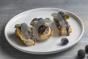 Traditional french eclairs with chocolate and blackberries