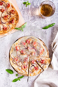 Traditional french flambee tart with cream cheese, bacon and onion on a board. Top and vertical view