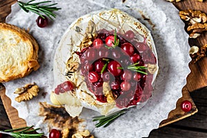 Traditional French homemade baked Camembert cheese with cranberries and nuts. rosemary and baguette bread