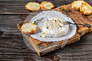 Traditional French homemade baked Camembert cheese with thyme and baguette bread. Gourmet traditional Breakfast close up