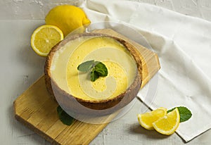 Traditional French Lemon Tart. Homemade pie dessert. Cake on wooden board and slice of fruit