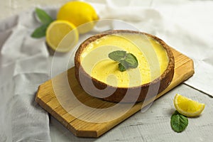 Traditional French Lemon Tart. Homemade pie dessert. Cake on wooden board and slice of fruit