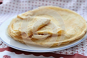 traditional french pancake homemade- in a plate on a red and white tablecloth
