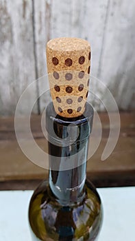 Traditional French wine bottle with brown dotted cork closeupon shabby wood backdrop