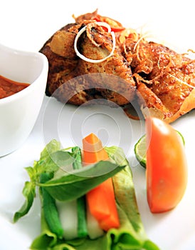 Traditional fried chicken with spices on top of it, vegetable condiment, white background, not crispy fried chicken