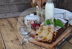 Traditional fruitcake with raisins, dried apricots, cherry for Christmas on wooden background. Sliced freshly baked cake and milk.