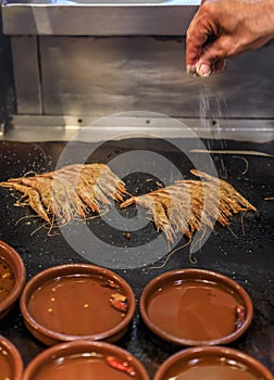 Traditional gambas a la plancha or grilled shrimp tapas being cooked on a hot plate in Madrid, Spain