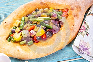 Traditional Georgian adjara khachapuri and Kolkh khachapuri with vegetables on the blue table.