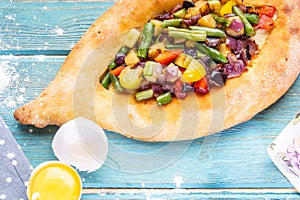 Traditional Georgian adjara khachapuri and Kolkh khachapuri with vegetables on the blue table.