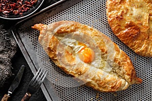 Traditional Georgian cheese bread on a dark background, close up view. Baked open pie with cheese and egg yolk filling