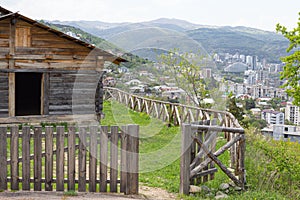 A traditional Georgian wooden farm building in Tbilisi Open Air Museum of Ethnography against the background of modern quarters of