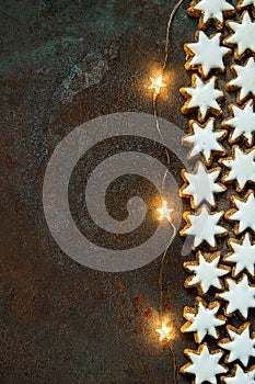 Traditional German Christmas Cookies Home Baked Glazed Cinnamon Stars with Nuts Sparkling Garland Lights on Rusty Dark Background