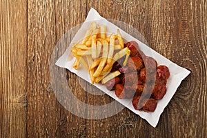 Traditional German currywurst, served with chips on disposable paper tray