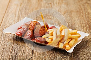 Traditional German currywurst, served with chips on disposable paper tray