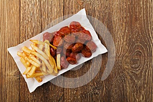 Traditional German currywurst, served with chips on disposable paper tray