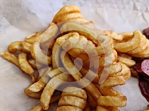 Traditional German currywurst, served with chips on a white plate. Wooden table as background