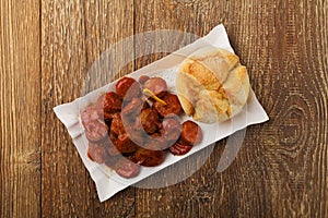 Traditional German currywurst, served on disposable paper tray with a fresh bun