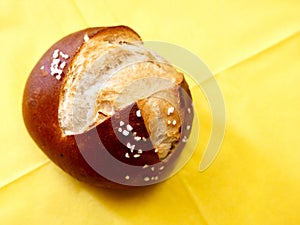 Traditional German lye bread roll with salt on yellow napkin