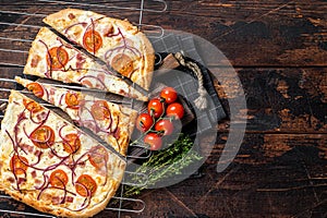 Traditional German pie Flammkuchen or tarte flambee with cream cheese, bacon, tomato and onions. Wooden background. Top