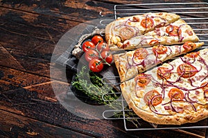 Traditional German pie Flammkuchen or tarte flambee with cream cheese, bacon, tomato and onions. Wooden background. Top