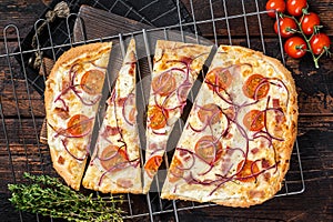 Traditional German pie Flammkuchen or tarte flambee with cream cheese, bacon, tomato and onions. Wooden background. Top