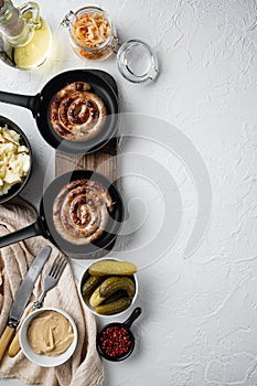 Traditional German Sausages with Mashed Potatoes and Sauerkraut in cast iron frying pan  on white background  top view flat lay