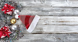 Traditional gold and silver balls, Santa cap plus gifts surrounded by tinsel on a white wood background for the Christmas or New