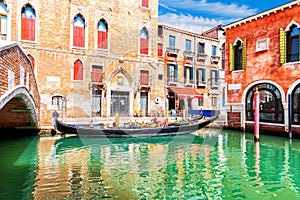Traditional gondola near the bridge by the typical palace of Venice, Italy