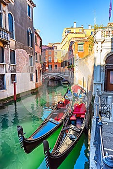 Traditional gondolas and bridge on narrow canal in Venice, Italy