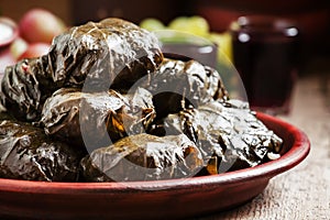 Traditional Greek dolma with meat in grape leaves, yogurt sauce, grapes and red wine on a clay dish, selective focus