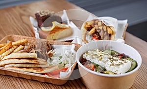 Traditional Greek fast food meal served in recyclable paper dishware. Pita souvlaki meat, fries, white tzatziki sauce and fresh