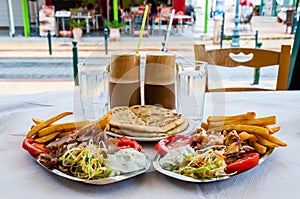 Traditional Greek hot dish Gyro or Gyros served on the plates. Pork or chicken meat, flat bread pita, tomato, tzatziki sauce, and