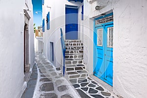 Traditional greek house with blue door and staircase in narrow city alley. Mykonos Island, Greece.