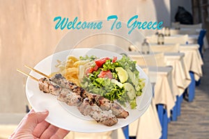A traditional greek pork souvlaki plate over a tavern background. Welcome to Greece concept