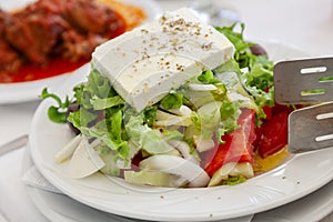 Traditional greek salad with a slice of feta cheese and olives served in tavern in Halkidiki, Greece